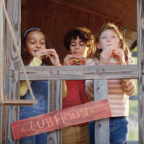 Children eating sandwiches in treehouse