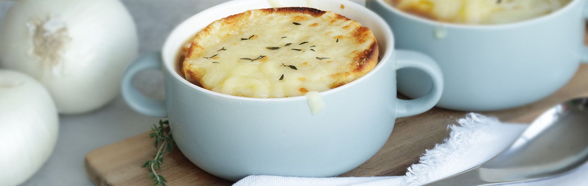 French Onion Soup, topped with half of an Artesano Brioche Bun, with melted Parmesan and Gruyere cheese